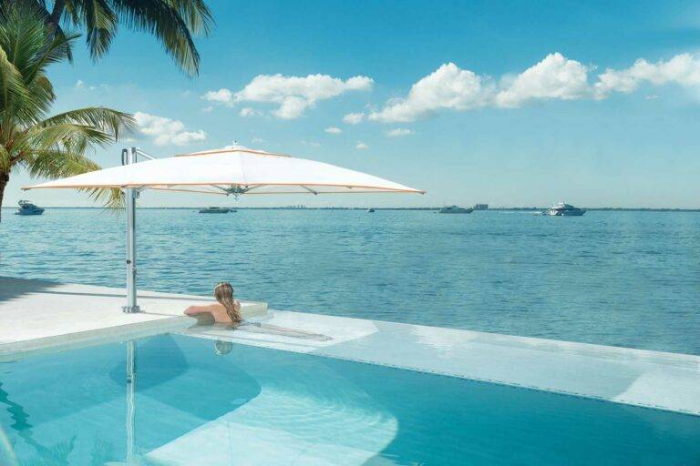 Lamellendach bietet perfekten Sonnenschutz: Entspannen unter blauem Himmel, neben einem Pool und stilvollen Outdoor-Möbeln.