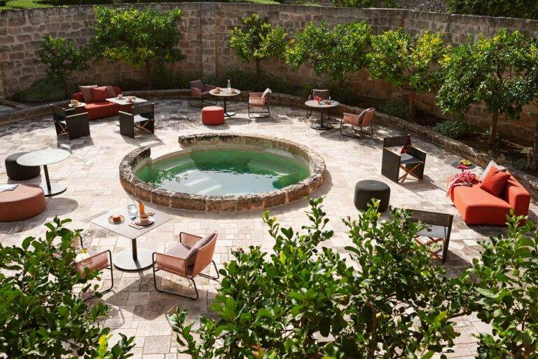Heller Außenbereich mit einem Pool in der Mitte und vielen Sitzgelegenheiten drum herum