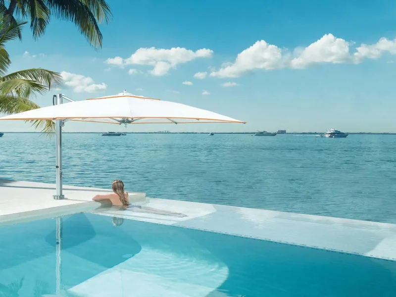 Lamellendach bietet perfekten Sonnenschutz: Entspannen unter blauem Himmel, neben einem Pool und stilvollen Outdoor-Möbeln.