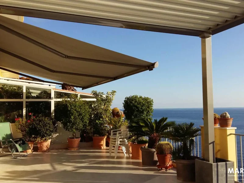 Markisen auf einer Terrasse, erleuchtet mit warmen Licht der Sonne mit Blick auf das Meer