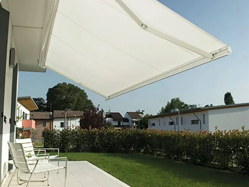 Sitzgelegenheit überdacht mit einer Markise, Rasenfläche im Hintergrund.