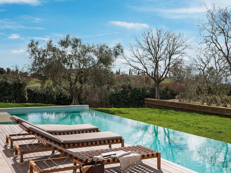 Sonnenliegen stehen in einem Garten am Pool