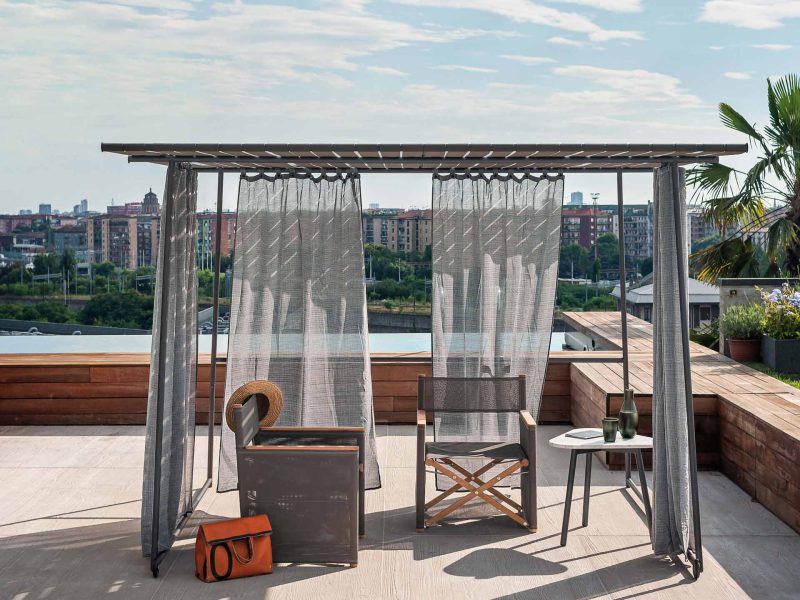 Pavillon steht in der Sonne auf einer Veranda mit Blick auf eine Stadt und Grün.