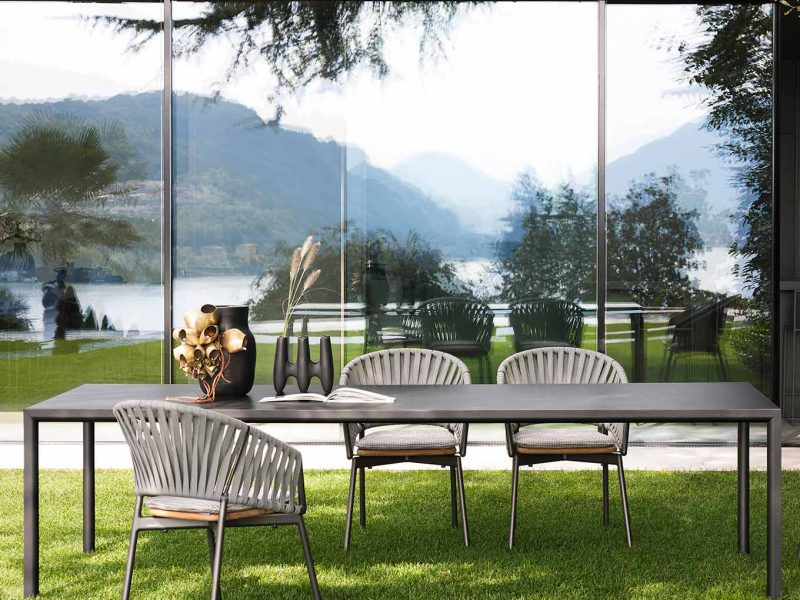 Stühle und Tische stehen unter einem Pavillon mit Blick auf Berge und See